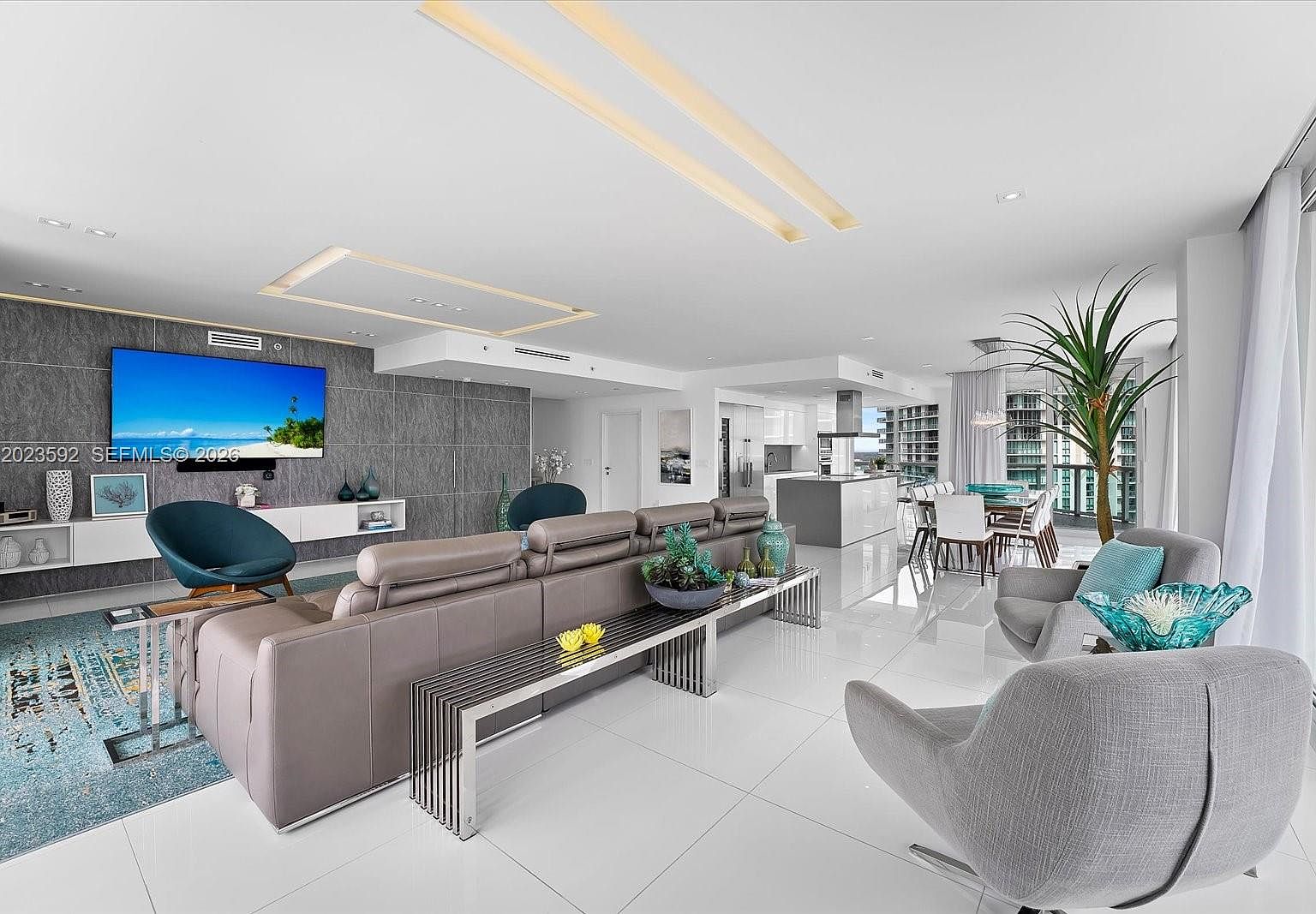Open-concept living and kitchen with a sculptural ceiling detail and uninterrupted floor of polished tile.